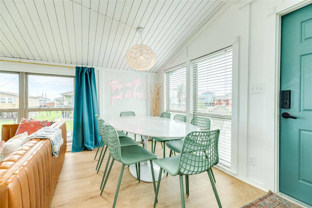 Bright and inviting dining area with a modern vibe, featuring a marble table, stylish chairs, and large windows offering plenty of natural light. Cozy seating and a playful neon sign adds charm.