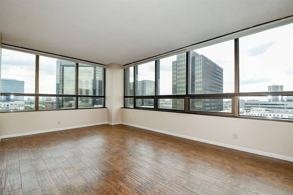 Primary bedroom with wood-look tile flooring. Views of downtown plus South views. Room for multiple pieces of furniture