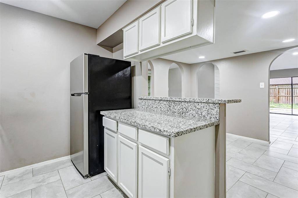 A perfect kitchen for entertaining, the granite breakfast bar transitions smoothly into the living area. The design offers an open concept feel while maintaining defined spaces. With updated cabinets and a spacious countertop, this kitchen balances practicality and elegance.