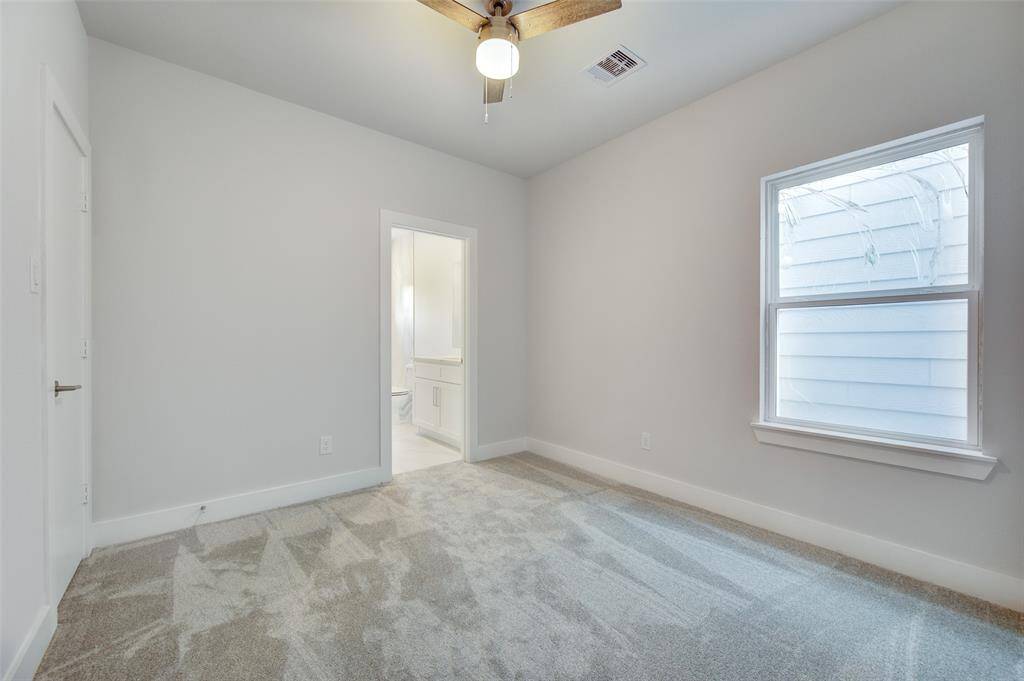 This spacious bedroom features plush carpeting, a ceiling fan for comfort, and large windows that allow plenty of natural light. The neutral palette provides a serene backdrop, perfect for rest and relaxation.