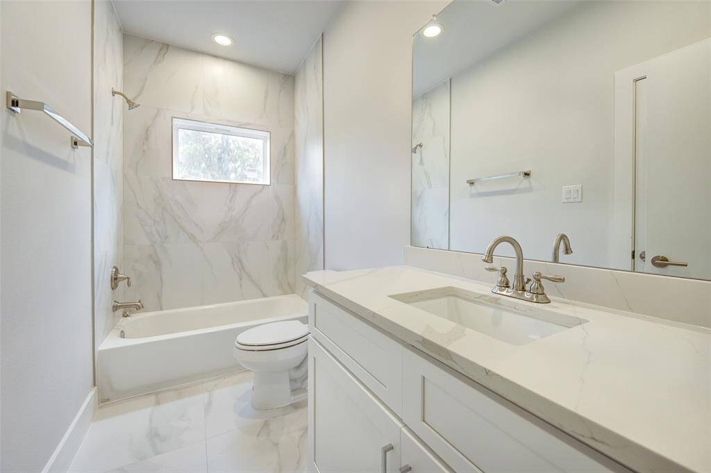 Enjoy a spa-like experience in this elegant bathroom, featuring a large vanity with ample counter space, a deep soaking tub, and a separate walk-in shower. The modern fixtures and marble tiles add a touch of luxury to your daily routine.