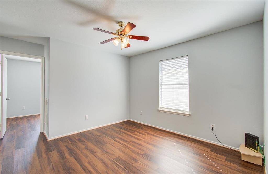 Another view of game room with vinyl floors, a ceiling fan, and ample natural light from a large window. It's a bright, versatile space suitable for another living room or home office.