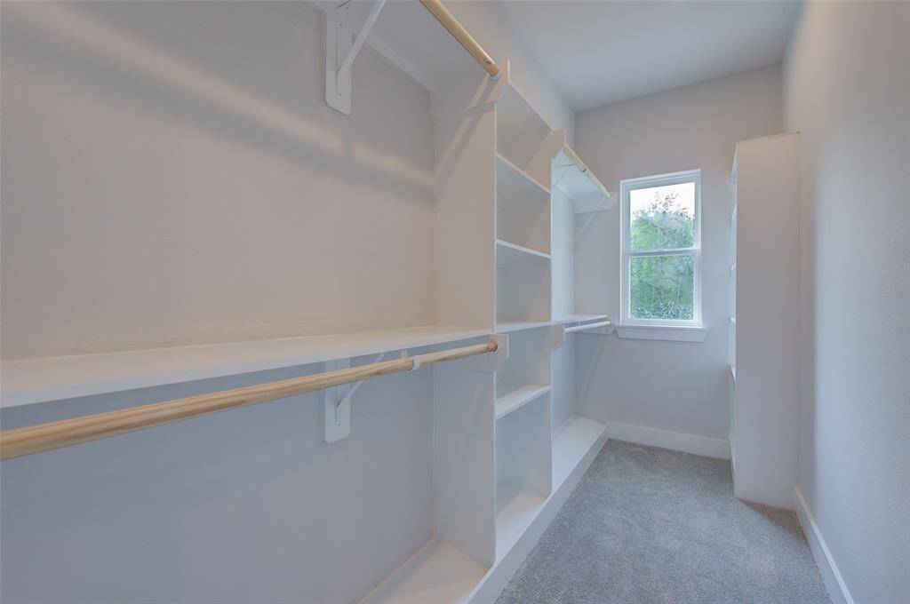 Ample storage space awaits in this walk-in closet, featuring custom shelving and hanging racks. The bright window provides natural light, making it easy to organize and find your wardrobe essentials.