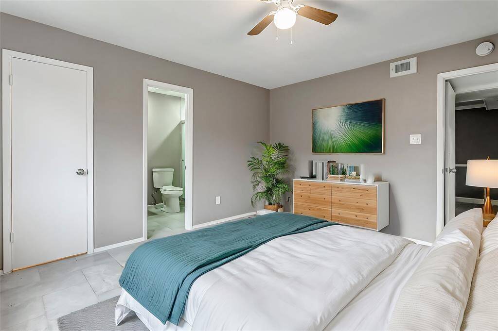 This bright and spacious bedroom offers neutral tones, fresh tile flooring, and a ceiling fan for comfort. Ample natural light filters through the large window, making it an ideal retreat for relaxation or a blank canvas for your personal style.