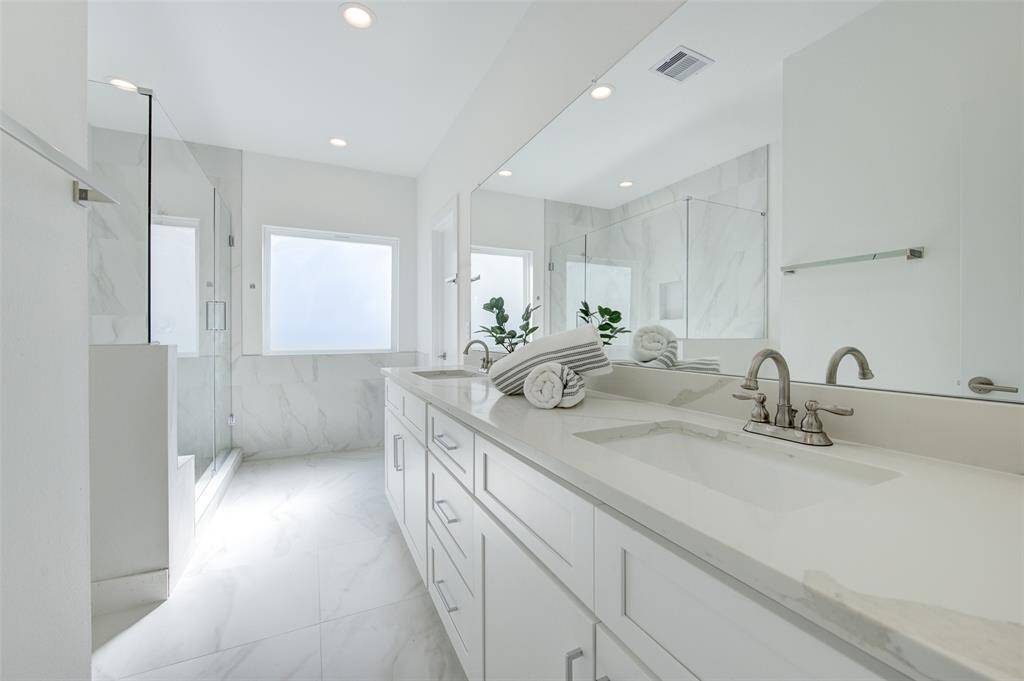 Indulge in the opulence of a spacious, light-filled bathroom featuring a dual vanity, elegant countertops, and a large walk-in shower. The modern design and high-end fixtures create a spa-like retreat.