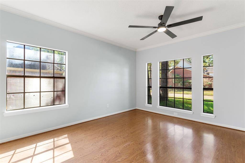 Bright Master bedroom with large windows, a ceiling fan, and light wood flooring.