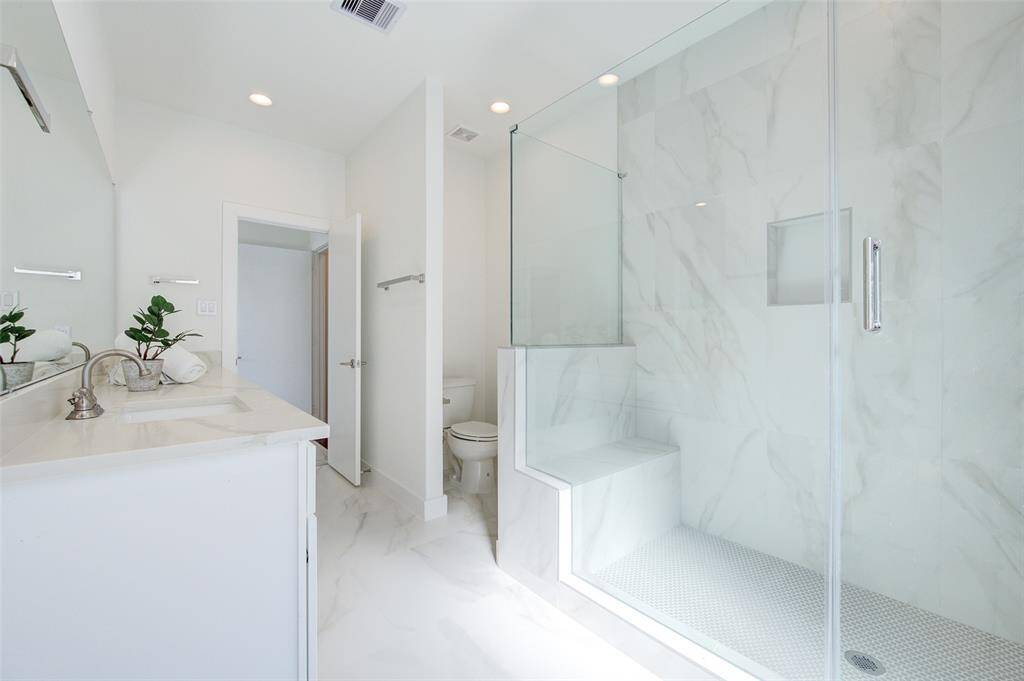 This beautifully designed shower boasts sleek glass doors, a built-in seat, and contemporary tilework. The spacious layout and high-quality finishes offer a luxurious start or end to your day.