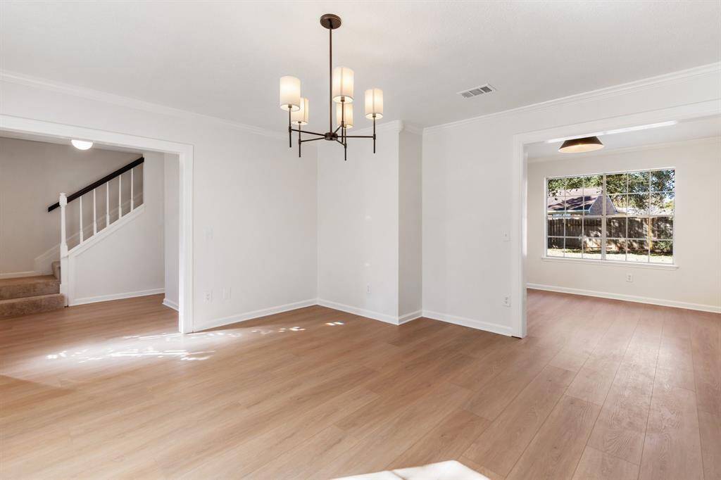 This dining room features large windows for natural light, a modern chandelier, and a stylish accent wall. (virtually staged)