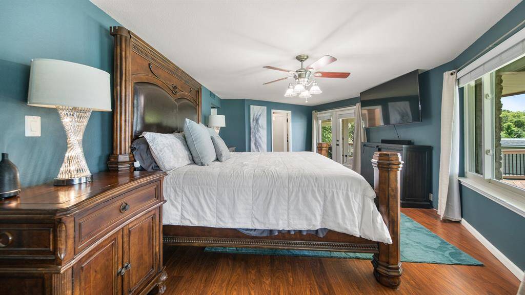 2nd Floor Primary Owner's Suite features Wood Flooring, Ceiling Fan & Stylish Paint Choice. Easy Access French Doors to 2nd Floor Deck & Heated LAP POOL.