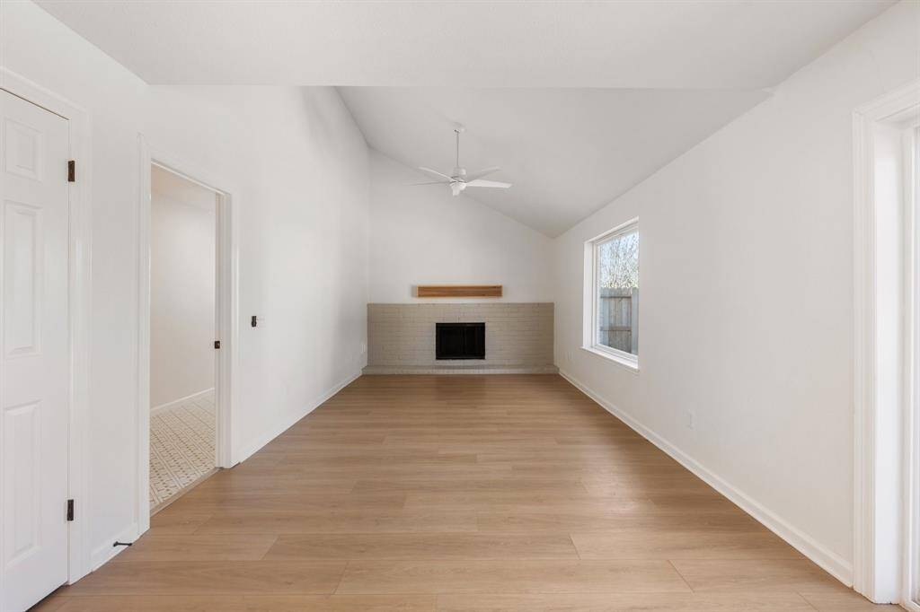 Spacious open living space features a vaulted ceiling, a cozy fireplace, and abundant natural light creating a warm, inviting atmosphere.