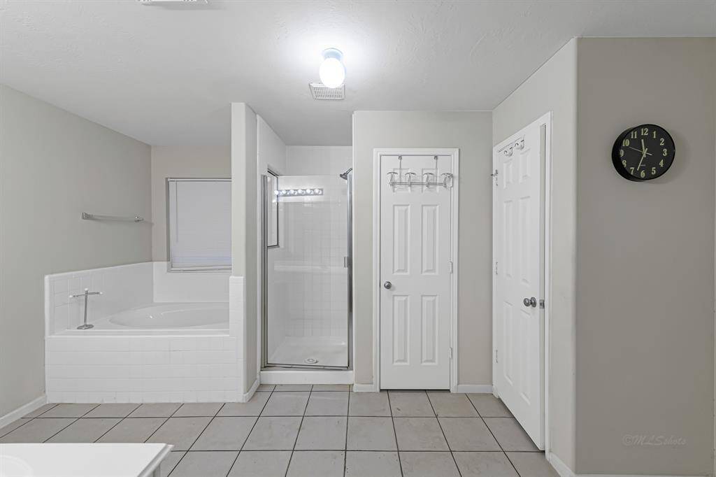 The shower area features a white tilesurround complemented by a framedenclosure. The room also includes alarge soaking tub that sits beneath awindow that allows natural lightwithout compromising privacy.