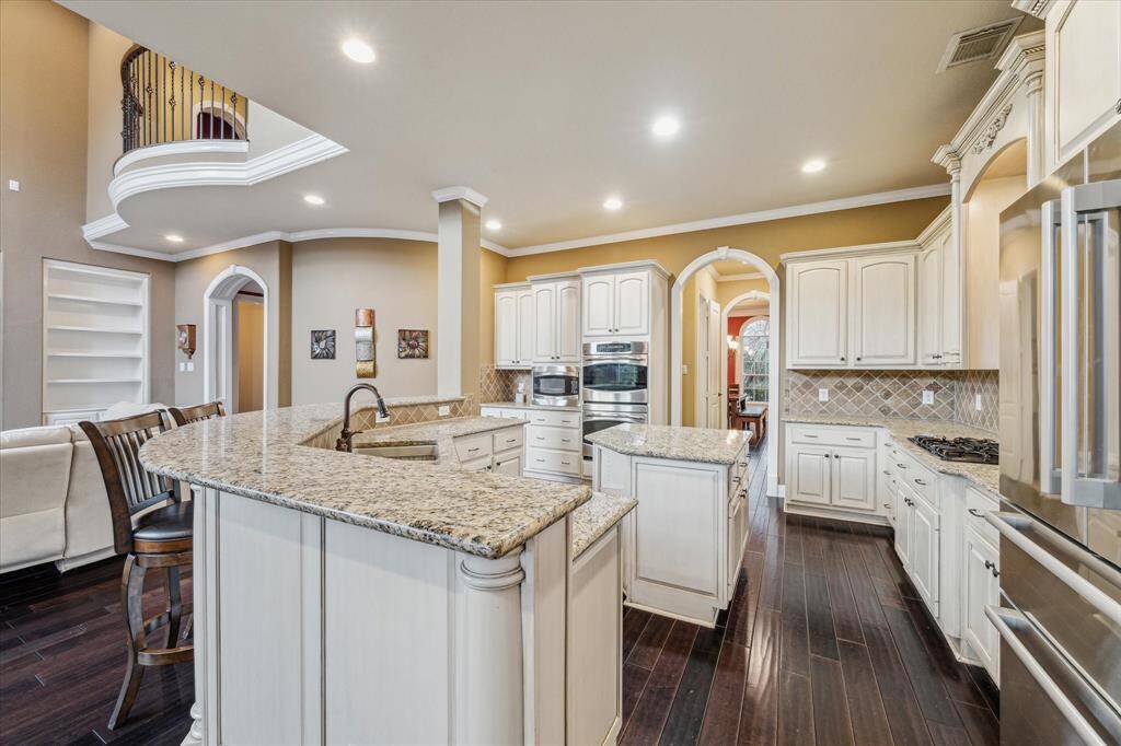 Spacious kitchen with abundant cabintry and stainless-steel appliances with bar seating.