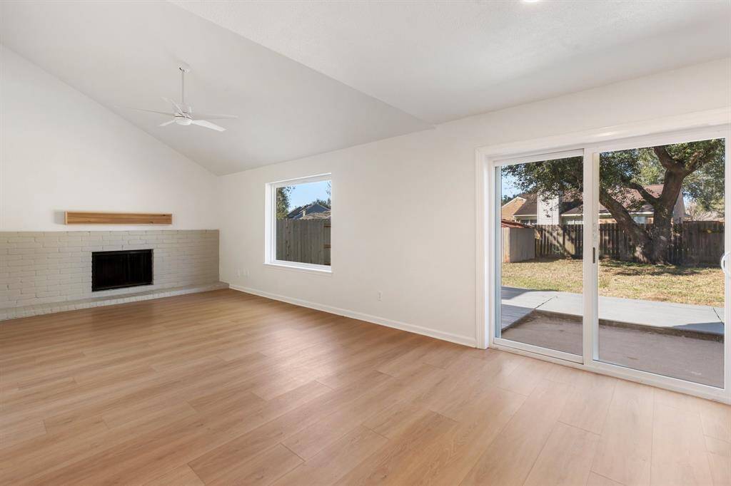 Spacious open living space features a vaulted ceiling, a cozy fireplace, and abundant natural light creating a warm, inviting atmosphere.
