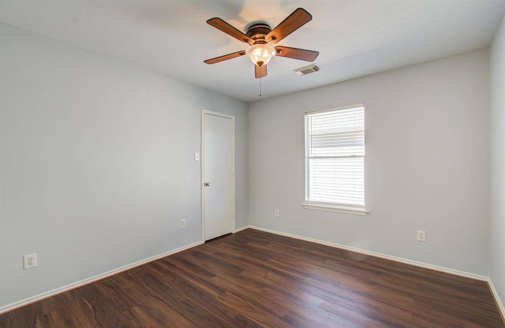 Fourth bedroom features light gray walls, vinyl flooring, a ceiling fan, and a window for natural light. It's a cozy, inviting space, perfect for a bedroom or home office.