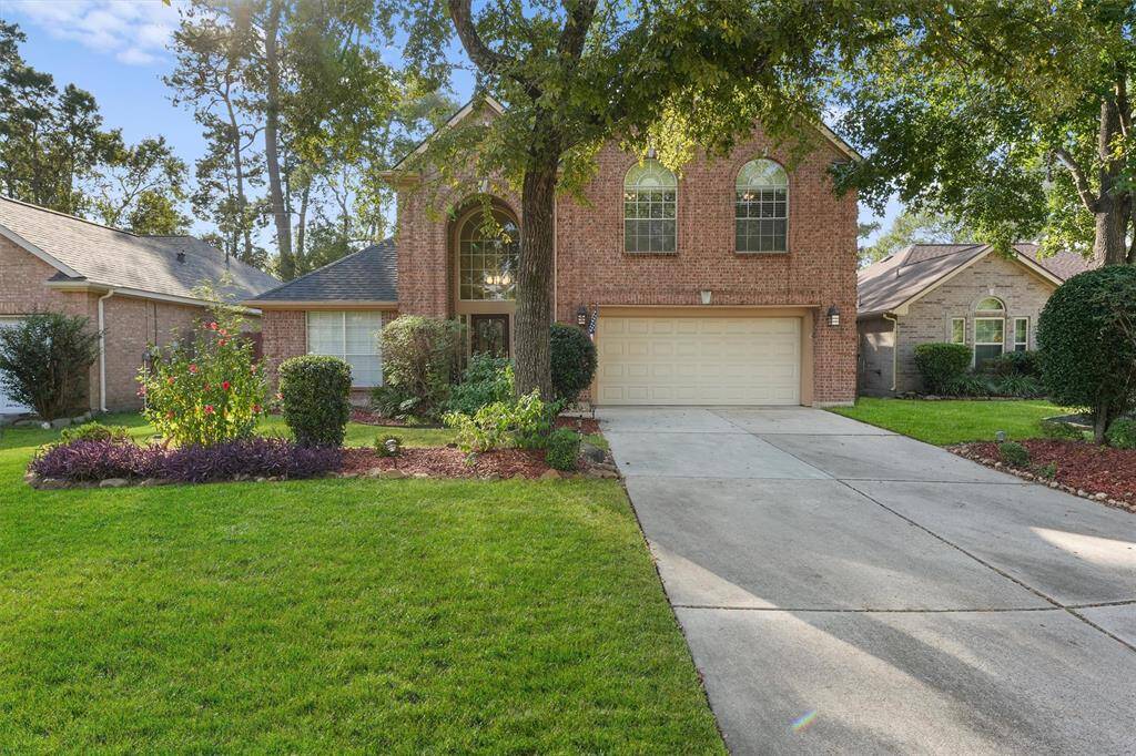 Beautiful two-story brick home with a two-car garage, arched windows and mature trees.
