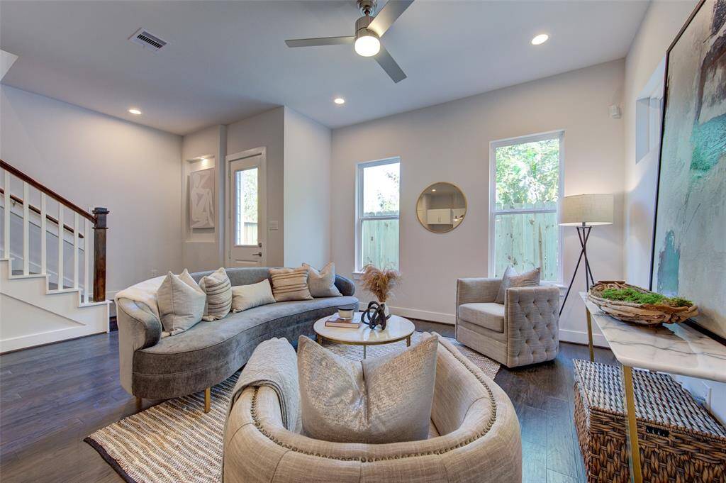 Welcome to a spacious living room featuring high ceilings and abundant natural light, complemented by engineered wood flooring. The modern design offers a cozy atmosphere perfect for relaxation and entertaining, while the open layout seamlessly connects to the rest of the home, ensuring a welcoming space for guests and family alike.