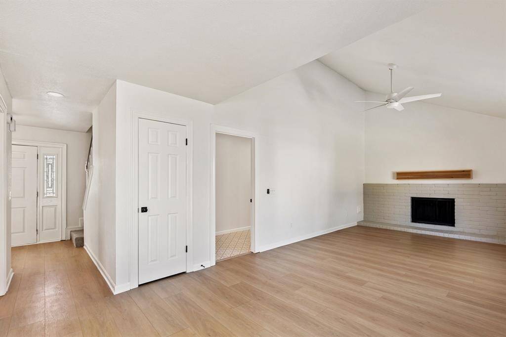 Spacious open living space features a vaulted ceiling, a cozy fireplace, and abundant natural light creating a warm, inviting atmosphere.