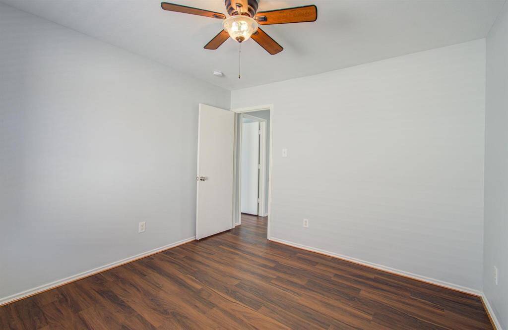 Another view of fourth bedroom features fresh, neutral walls and luxury vinyl flooring, complemented by a ceiling fan for comfort. The space is well-lit and inviting, ideal for customization.