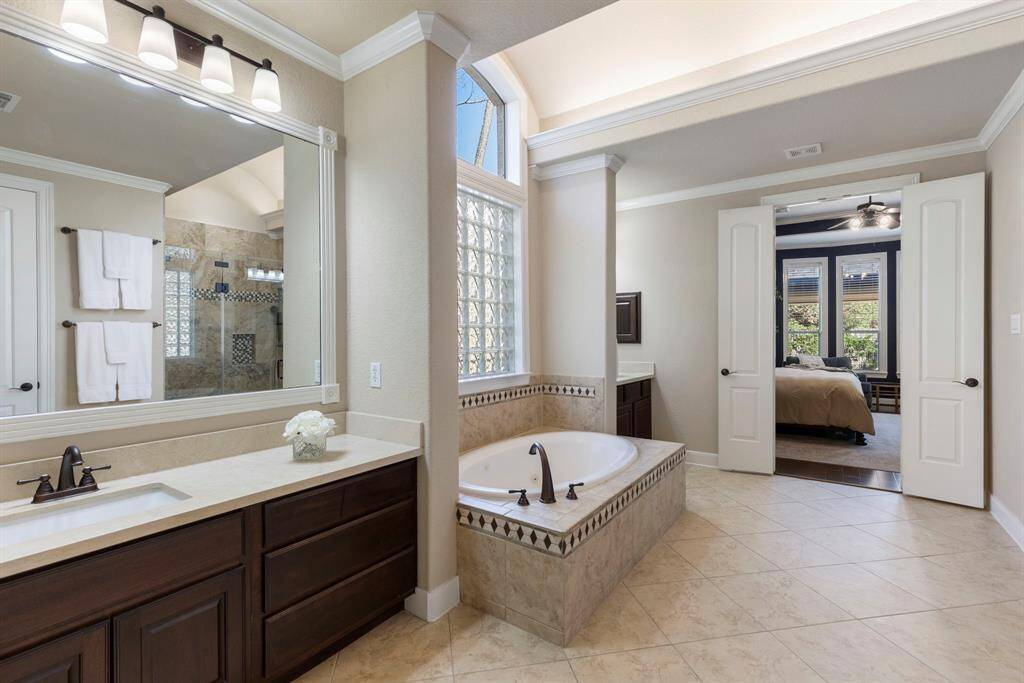 The spacious primary bathroom offers a luxurious retreat, featuring dual vanities with his & hers sinks, a relaxing jetted tub, and a large shower, providing both comfort and convenience for daily living.