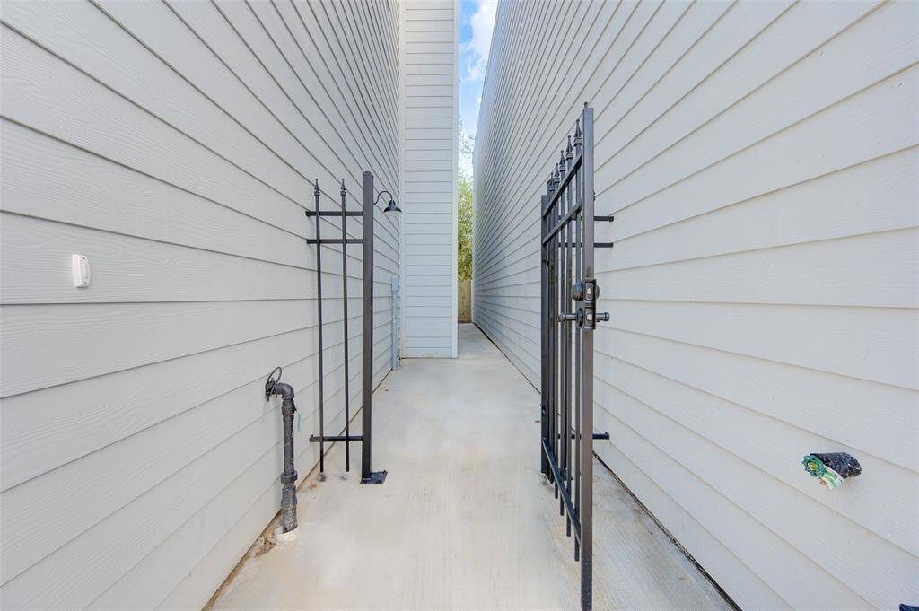 The secure gated entry ensures both privacy and security, leading to a low-maintenance concrete path that connects the front and back of the property seamlessly.