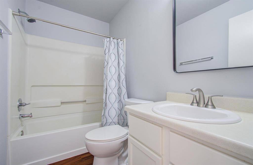 Second bathroom features a clean, modern design with a bathtub and shower combo, a vanity with a sink, and a large mirror. The neutral color palette offers a fresh and inviting feel.