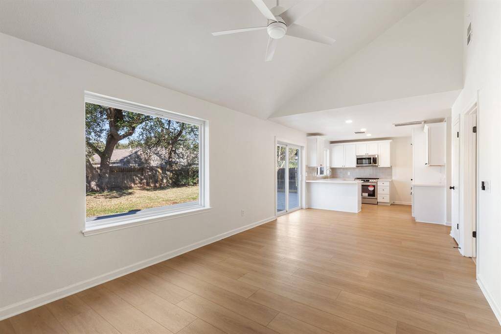 Spacious open living space features a vaulted ceiling, a cozy fireplace, and abundant natural light creating a warm, inviting atmosphere.