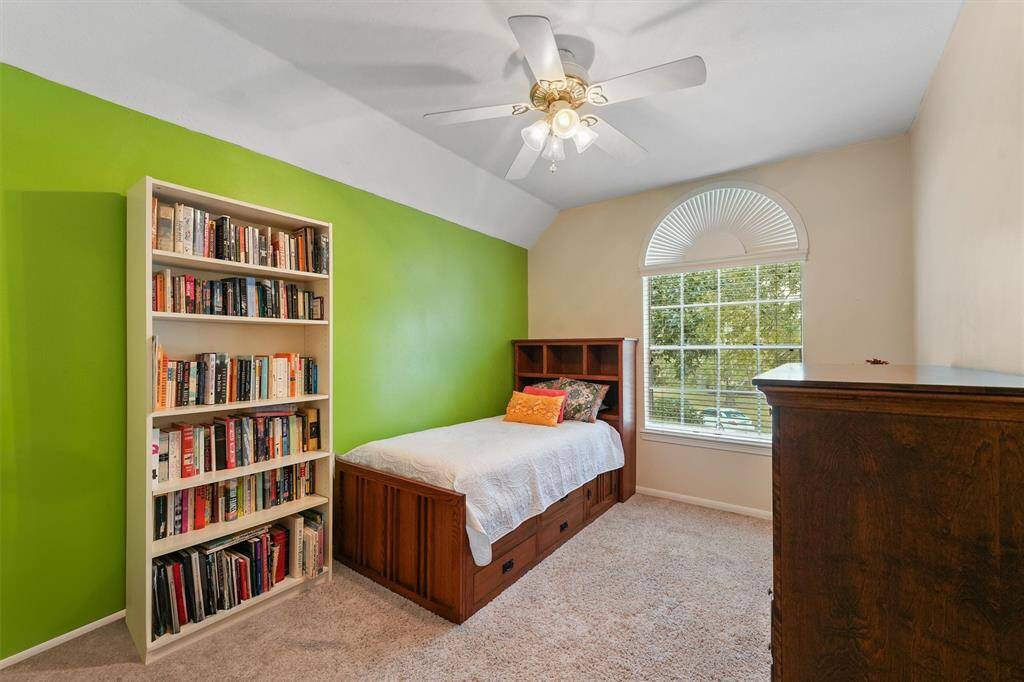 This is a bright 3rd  bedroom featuring  a ceiling fan, a large window allowing for plenty of natural light.