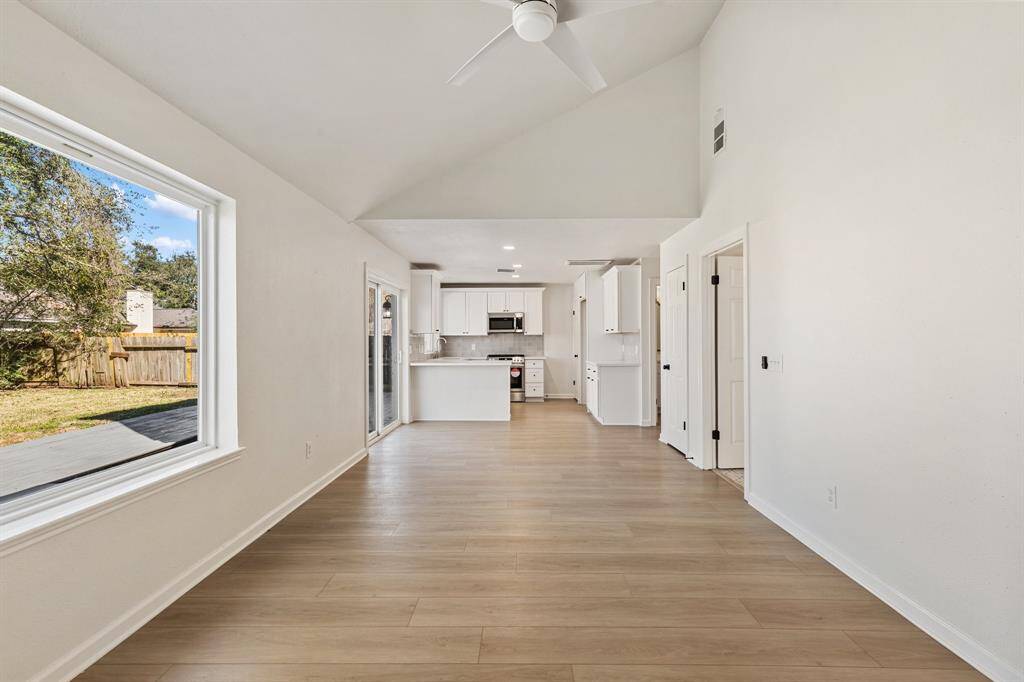 Spacious open living space features a vaulted ceiling, a cozy fireplace, and abundant natural light creating a warm, inviting atmosphere.