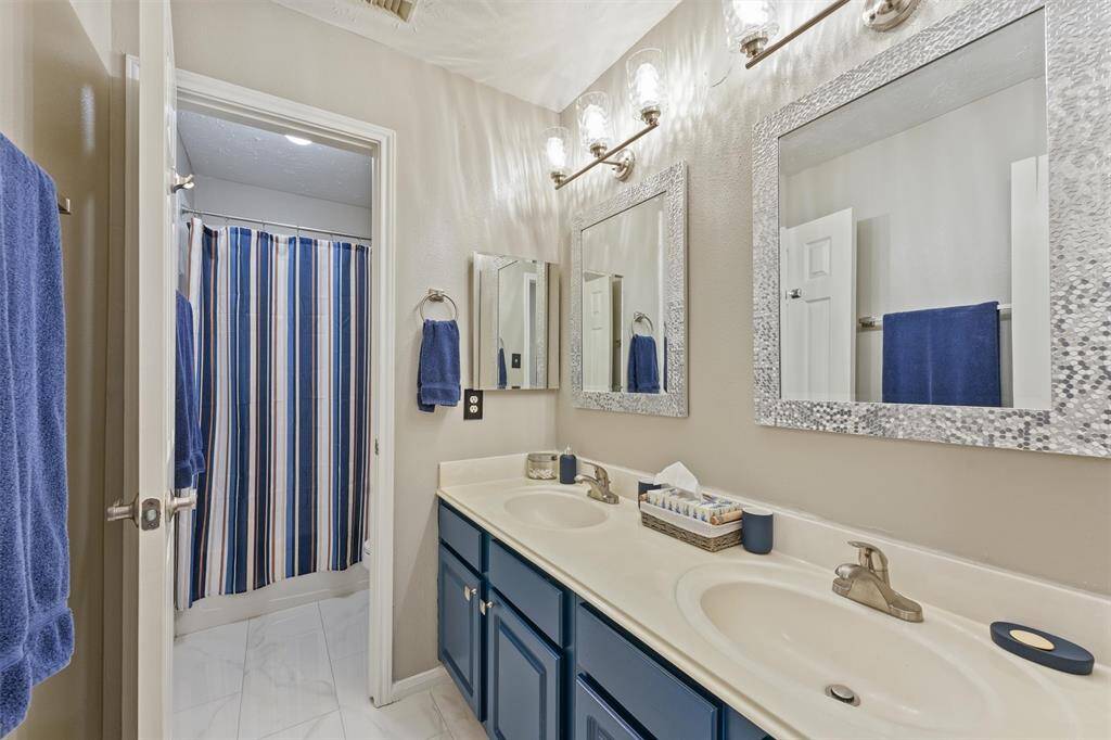 This is well-lit bathroom features a dual-sink vanity with a large mirrors, and a tub/shower combo. The space has a clean, contemporary feel.