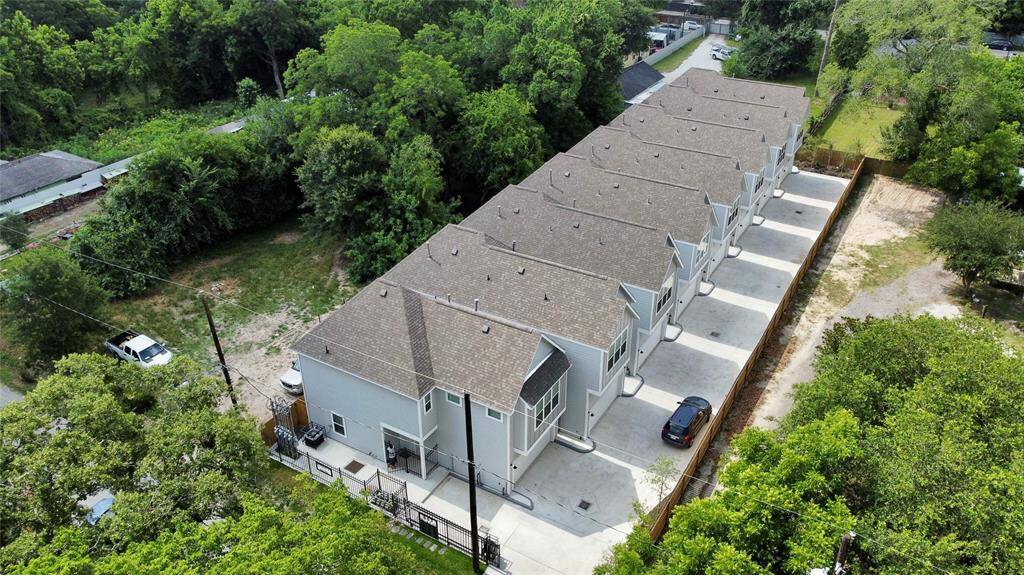 This aerial view highlights the row of contemporary townhomes, each with its own driveway and secure parking. Surrounded by lush greenery, the community offers a tranquil yet convenient living environment.