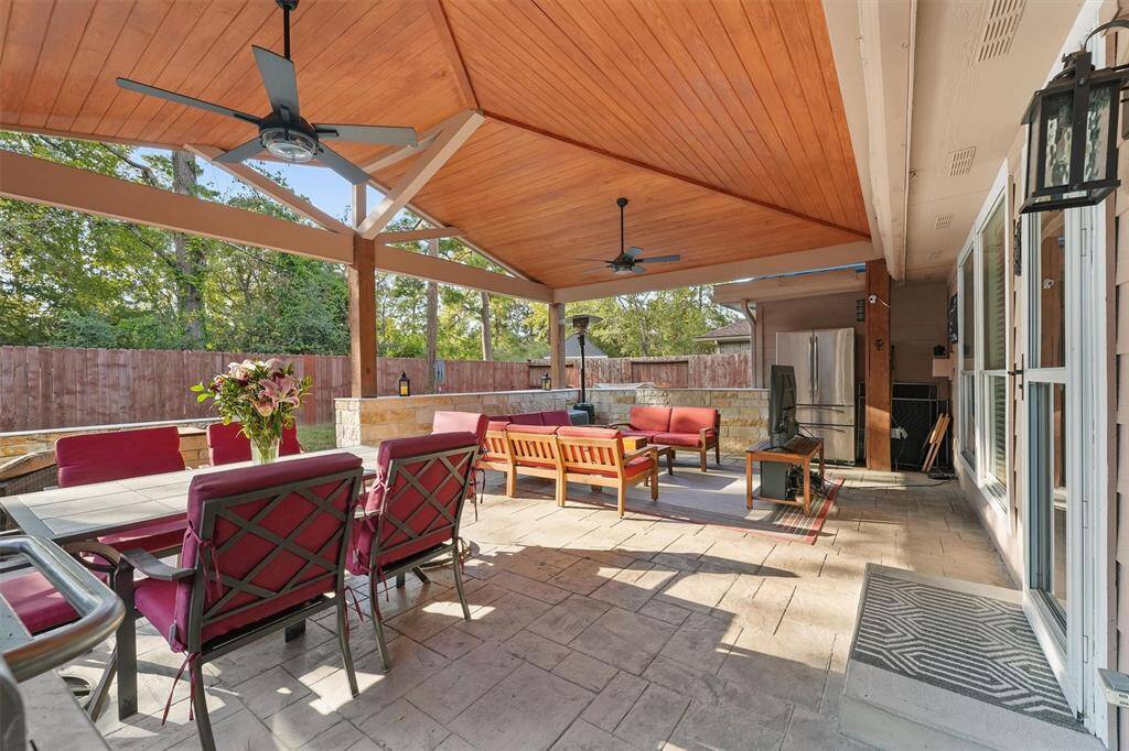Look at this spacious and inviting covered outdoor patio with a wooden ceiling and fans, perfect for dining and relaxation, overlooking a private fenced backyard with access to the greenbelt, park and pool.