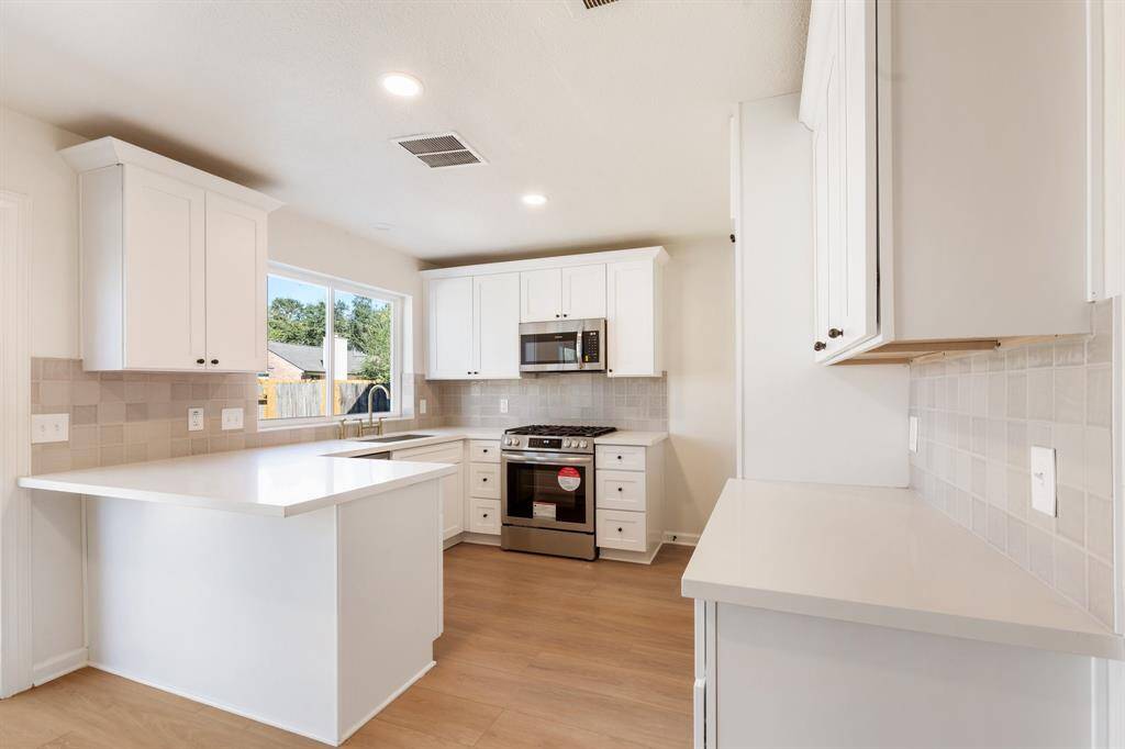 Bright, modern kitchen with white cabinetry and stainless-steel appliances. Features ample natural light and an open layout, perfect for cooking and entertaining.