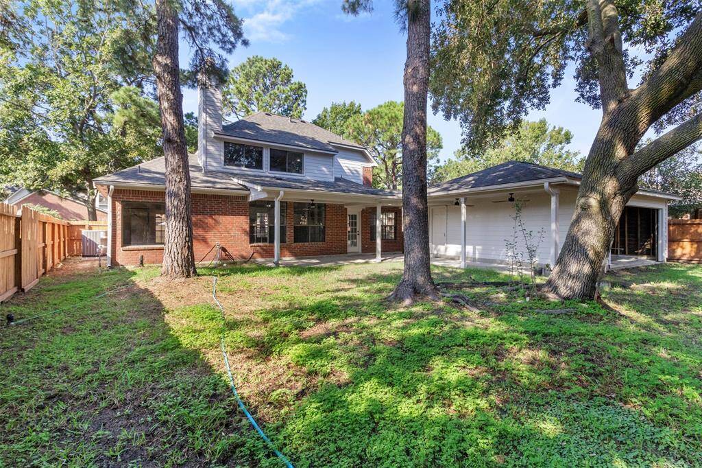 Charming two-story home with a brick and siding exterior, nestled among mature trees. Features a spacious backyard with a wooden fence, perfect for outdoor activities and relaxation.