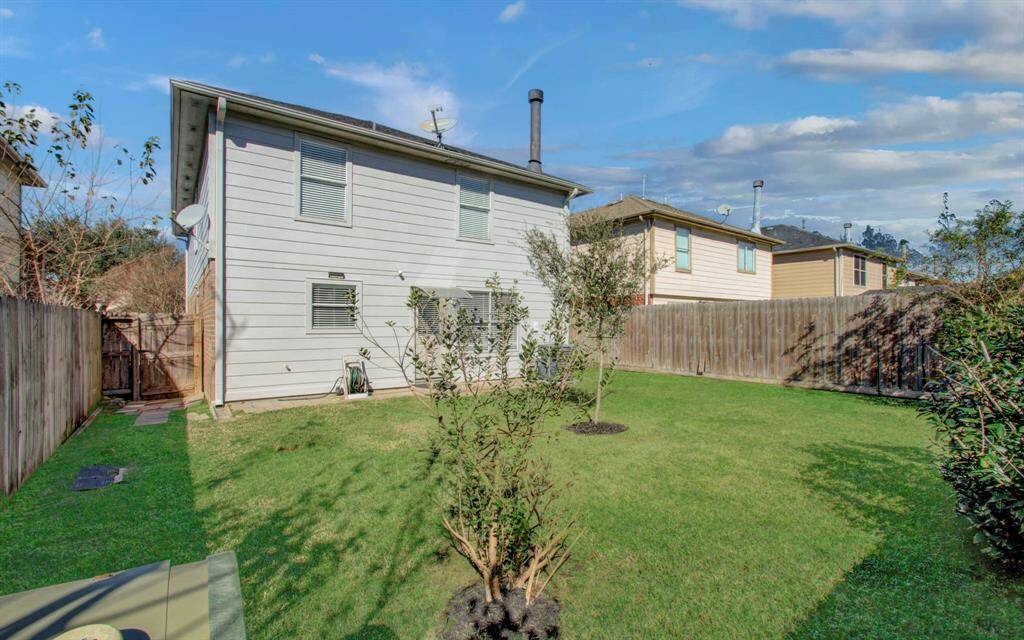 Another view of charming backyard with lush green lawn, trees, and wooden fencing for privacy. Perfect for outdoor activities and relaxation.