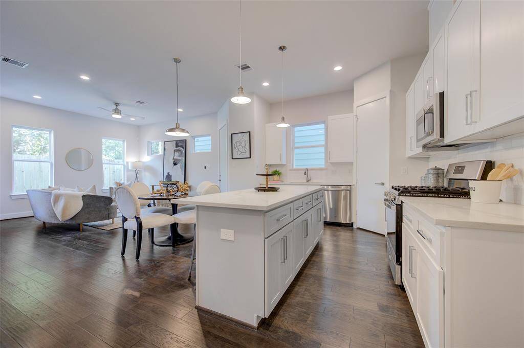 This contemporary kitchen is a chef's dream with its expansive quartz countertops, stainless steel appliances, and ample cabinet space. The large kitchen island provides additional workspace and is perfect for casual dining or social gatherings. The open-concept design ensures the kitchen flows effortlessly into the living and dining areas, creating a cohesive and inviting environment.
