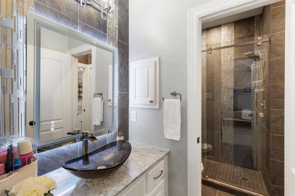 The secondary Jack & Jill bathroom has been thoughtfully updated with sleek, modern finishes, including a control touch mirror and a beautifully designed shower, offering both style and functionality.