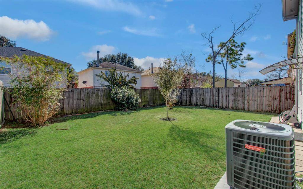 Another view of the backyard with spacious lawn, bordered by a wooden fence.