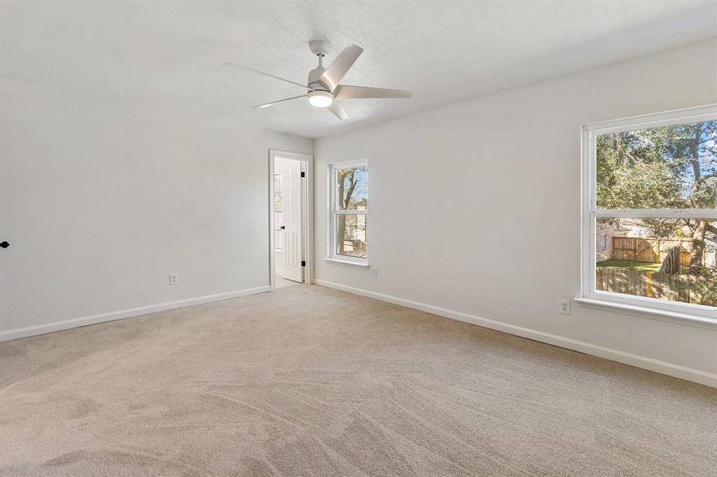 Bright and spacious primary bedroom featuring large windows for natural light and a ceiling fan, ideal for relaxation.