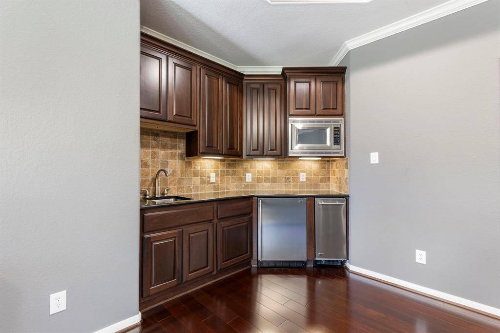 The wet bar adds convenience to the game room, equipped with a microwave, refrigerator, and sink, making it the perfect spot for refreshments while enjoying entertainment and games.