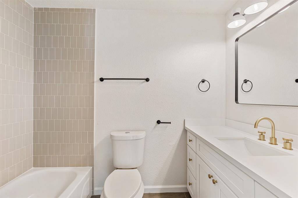 This 2nd bathroom features a modern design and a neutral tiled bathtub.