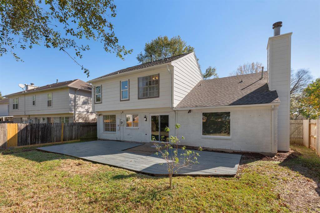 Backyard with a spacious wooden deck, a fenced yard, and mature trees, perfect for relaxations and entertaining.