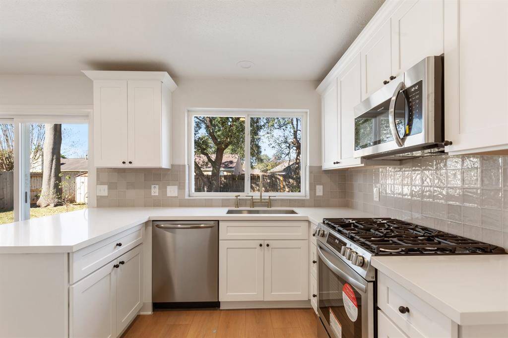 Bright kitchen with modern appliances, white cabinetry, an abundance of natural light.
