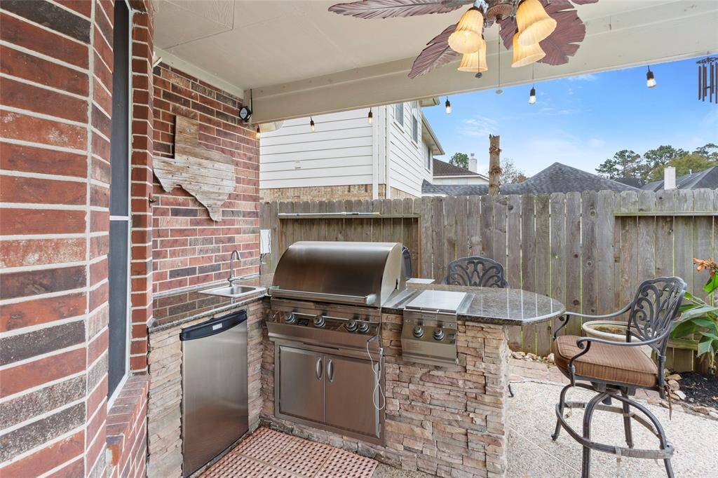 Outdoor kitchen with stacked stone, granite counter plus Fire Magic Grill, refrigerator and sink.