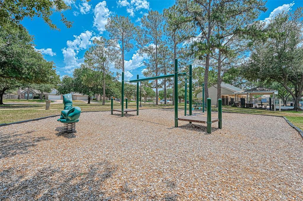 This photo shows a neighborhood playground with swings and play structures, surrounded by trees and a nearby picnic area. It's a family-friendly spot, perfect for outdoor activities.