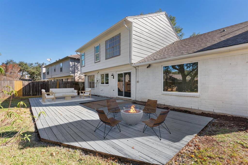 Backyard with a spacious wooden deck, a fenced yard, and mature trees, perfect for relaxations and entertaining.
