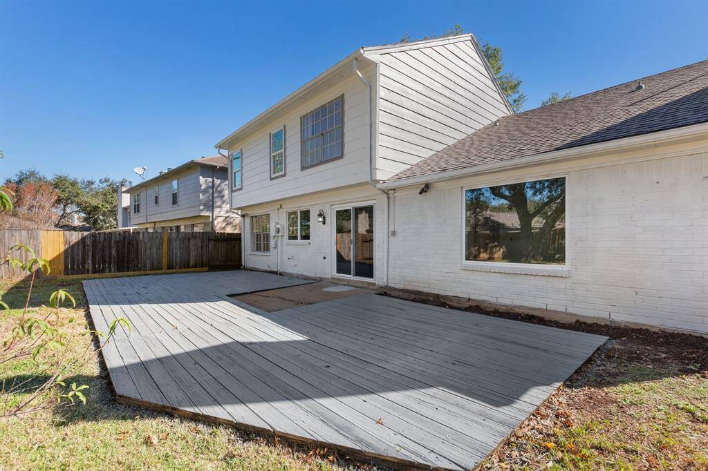Backyard with a spacious wooden deck, a fenced yard, and mature trees, perfect for relaxations and entertaining.
