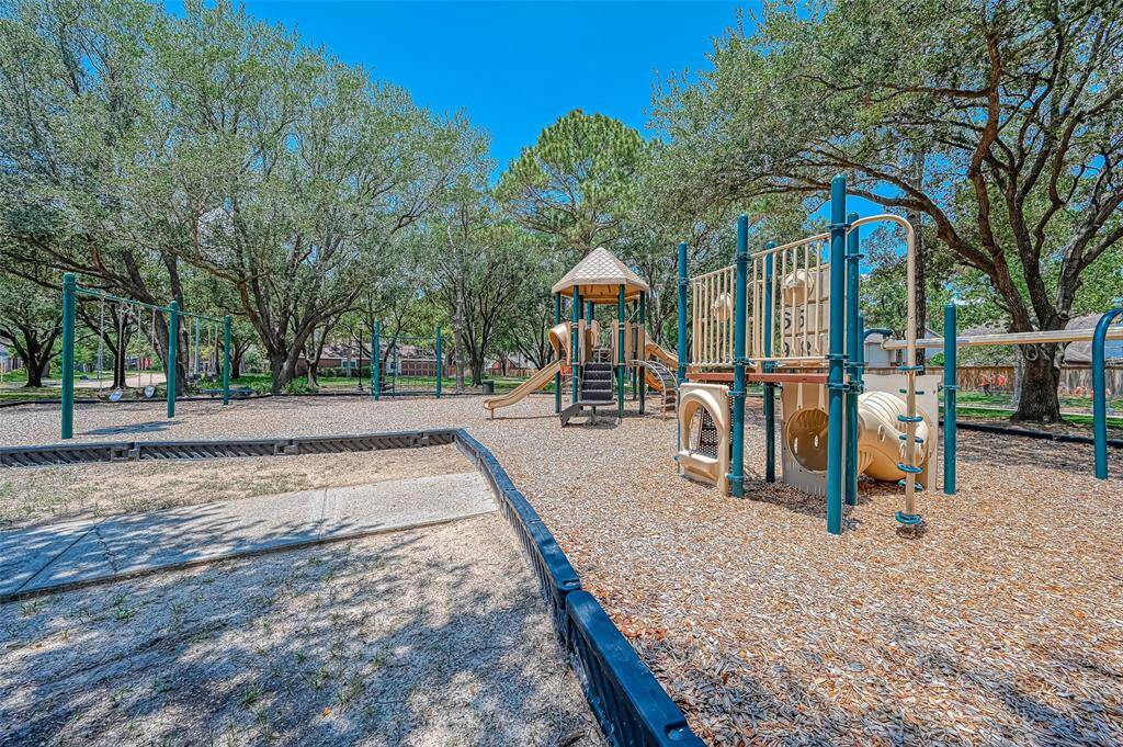 This photo shows a well-maintained playground surrounded by mature trees, providing shade and a family-friendly environment. Ideal for families looking for nearby recreational spaces.