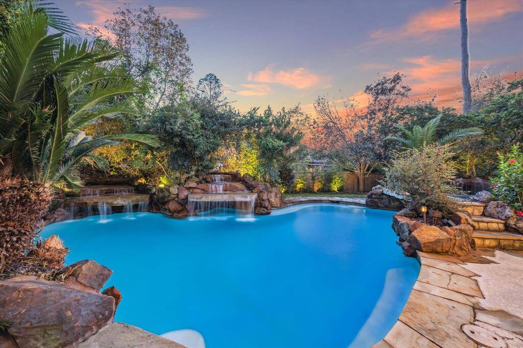Beautiful flagstone surrounding the pool and waterfalls with lush landscape.