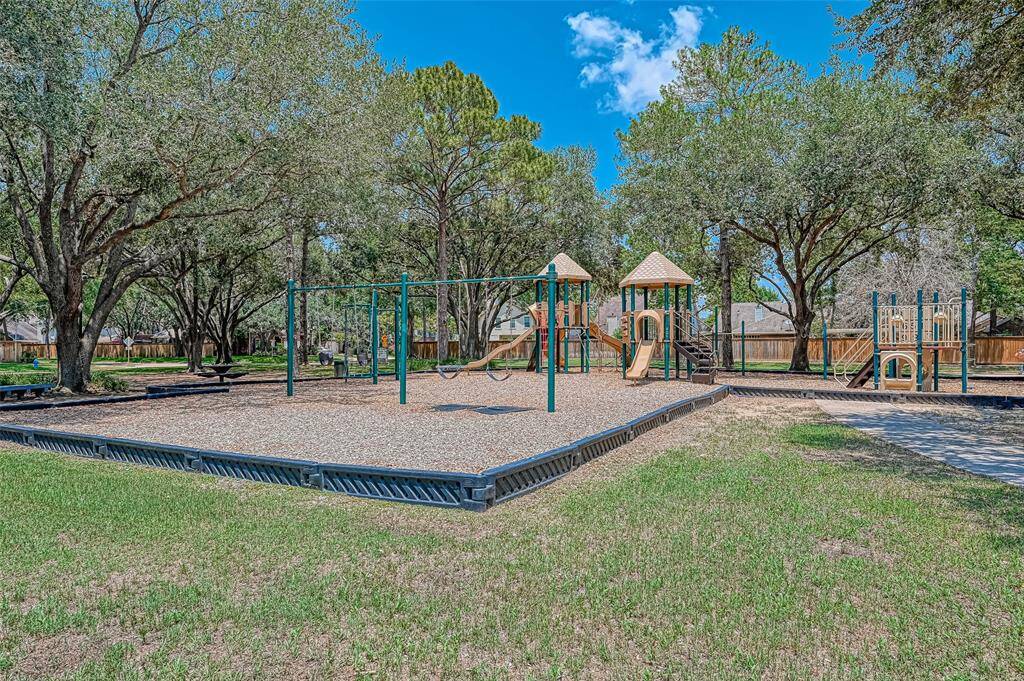 This photo shows a spacious playground surrounded by trees, featuring swings, slides, and climbing structures, perfect for families.