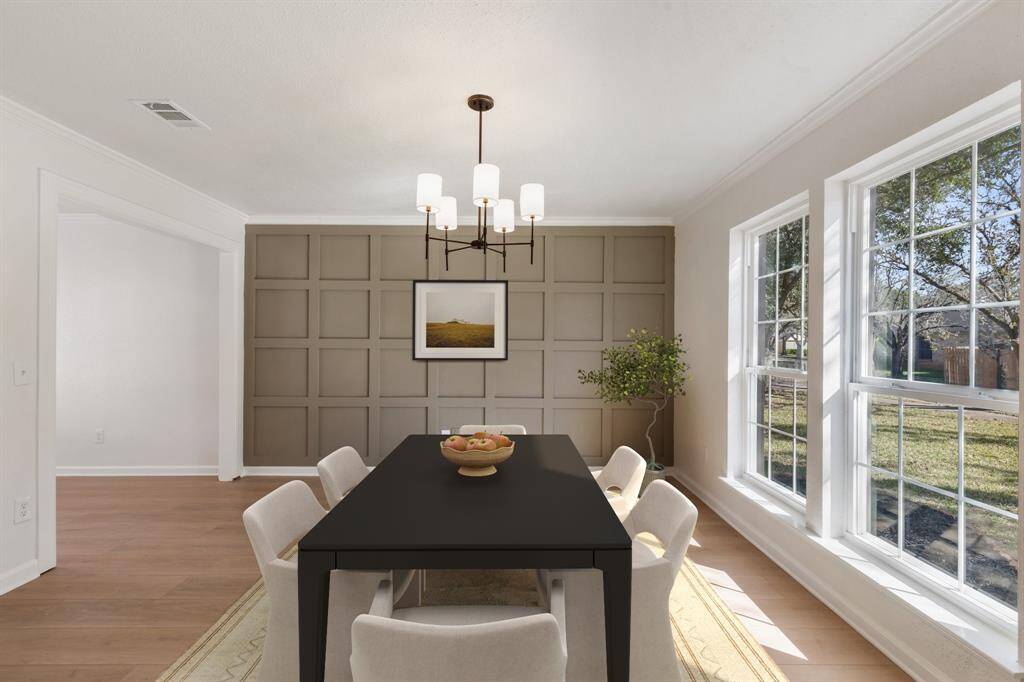 This dining room features large windows for natural light, a modern chandelier, and a stylish accent wall. (virtually staged)